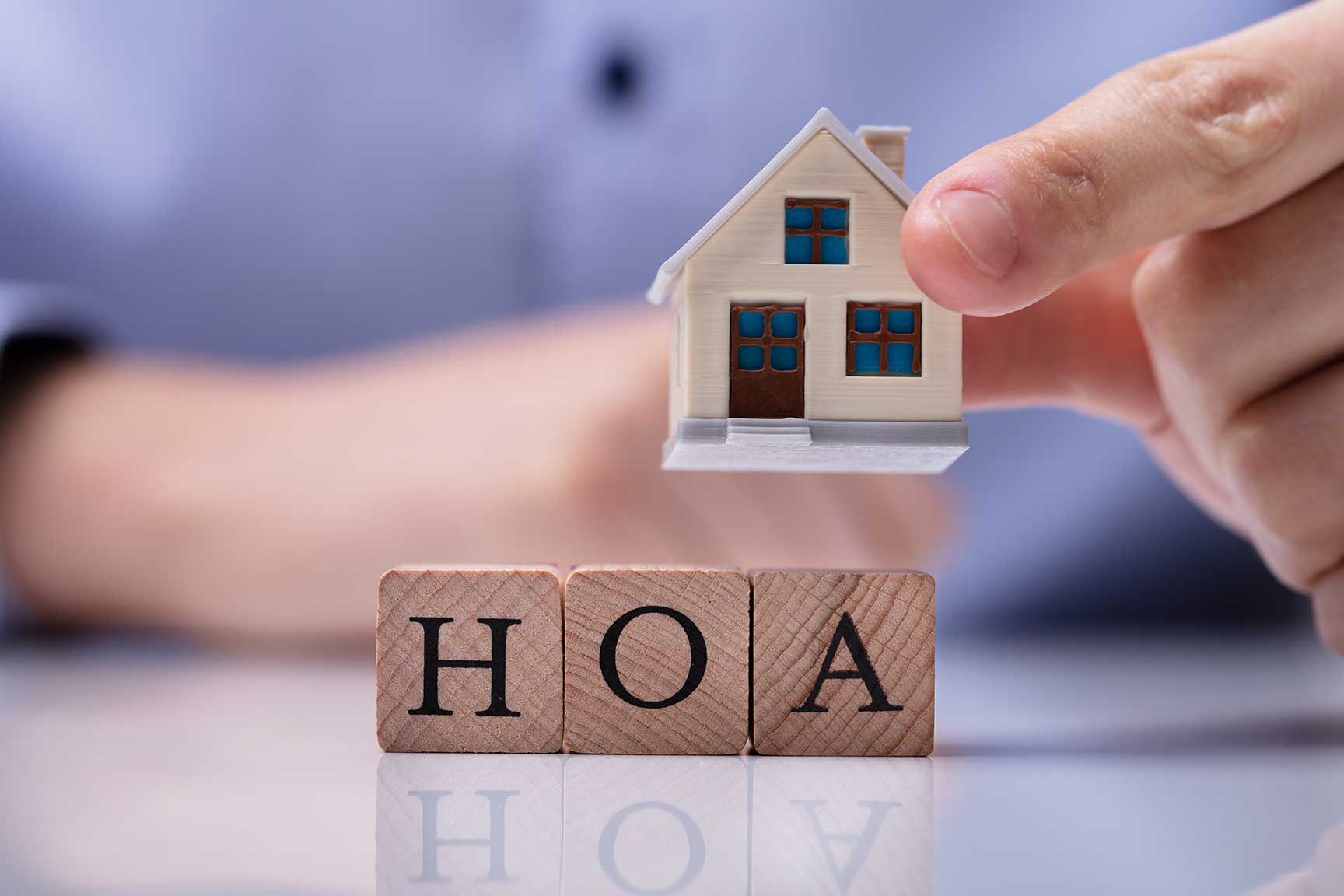 Miniature home with scrabble tiles that read HOA.